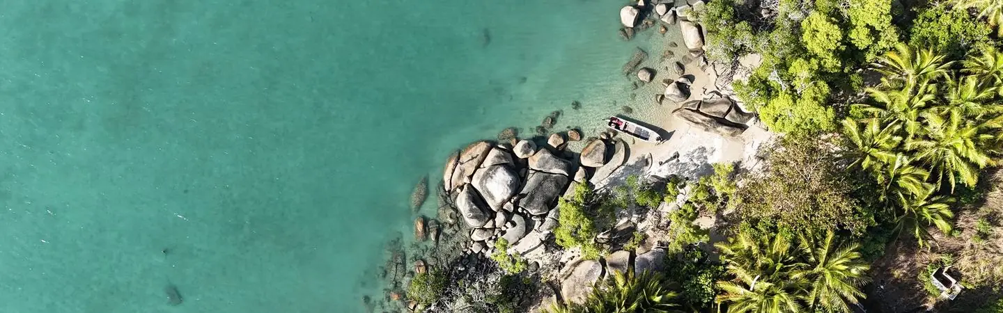 Aerial view of a rocky, forested Torres Strait coastline